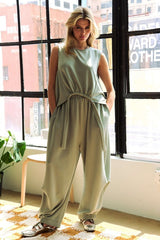 Woman in a light green drawstring hem round neck tank and pants set, showcasing casual and stylish comfort indoors.