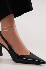 Black faux leather point toe slingback pump worn with a delicate ankle bracelet, showcasing elegance and style.