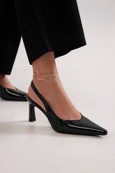 Black faux leather point toe slingback pumps showcased with chic ankle accessories, perfect for stylish outings.