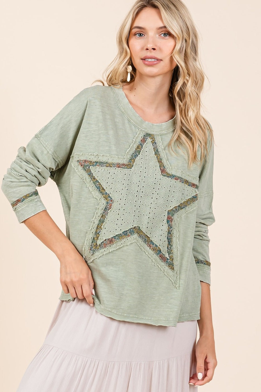 A woman wearing a green long sleeve t-shirt with a star patch