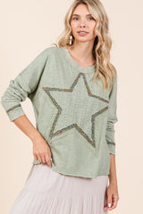 A woman wearing a green long sleeve t-shirt with a star patch