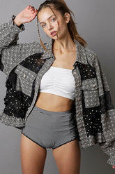 Model showcasing a stylish black and white patchwork jacket over a white crop top and striped high-waisted shorts.