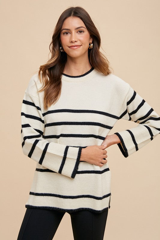 Woman wearing a striped round neck sweater with side slits, styled for a modern and fashionable look.