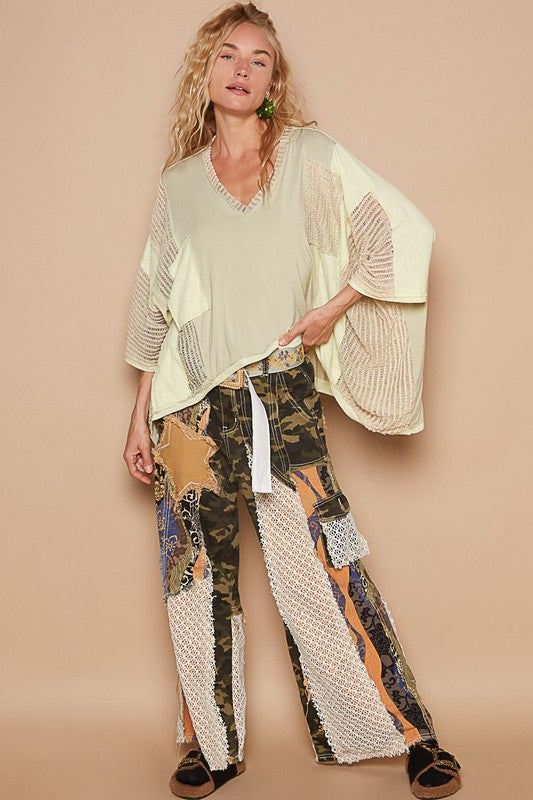 Model wearing a POL high-low contrast V-neck top with oversized fit, paired with unique patchwork pants for a chic look.