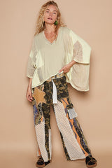 Model wearing a POL high-low contrast V-neck top with oversized fit, paired with unique patchwork pants for a chic look.