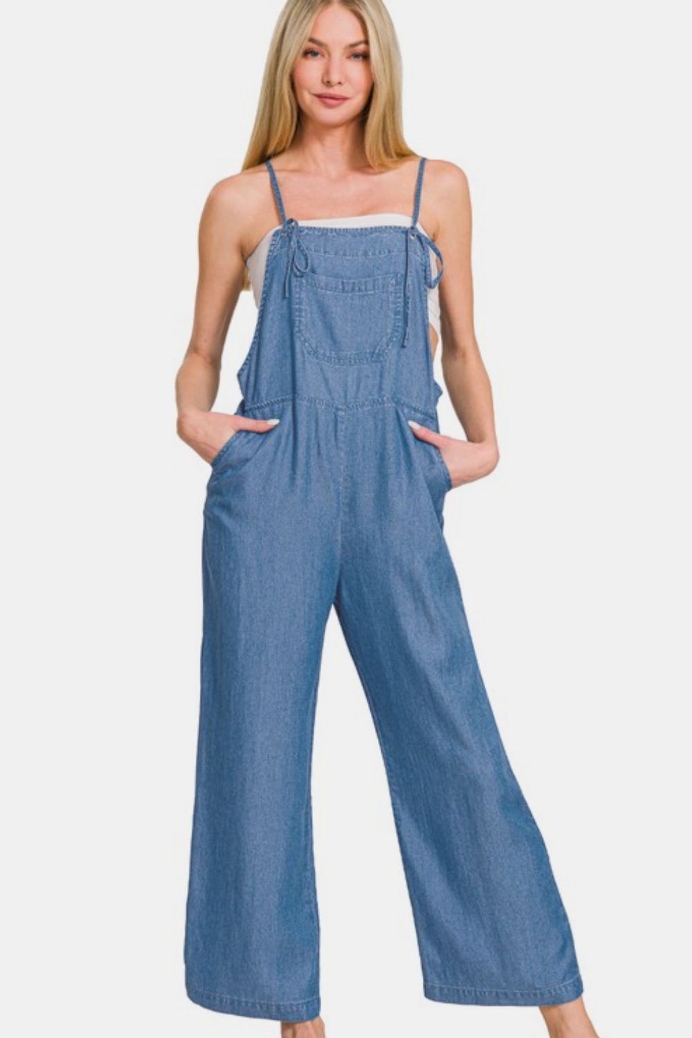 Woman in washed adjustable strap wide leg denim overalls, showcasing a trendy and relaxed casual look.
