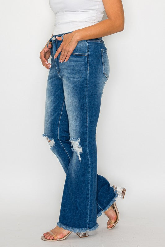 Woman wearing bytos Full Size Raw Hem Distressed High Rise Bootcut Jeans with a white top and sandals, showcasing a trendy look.