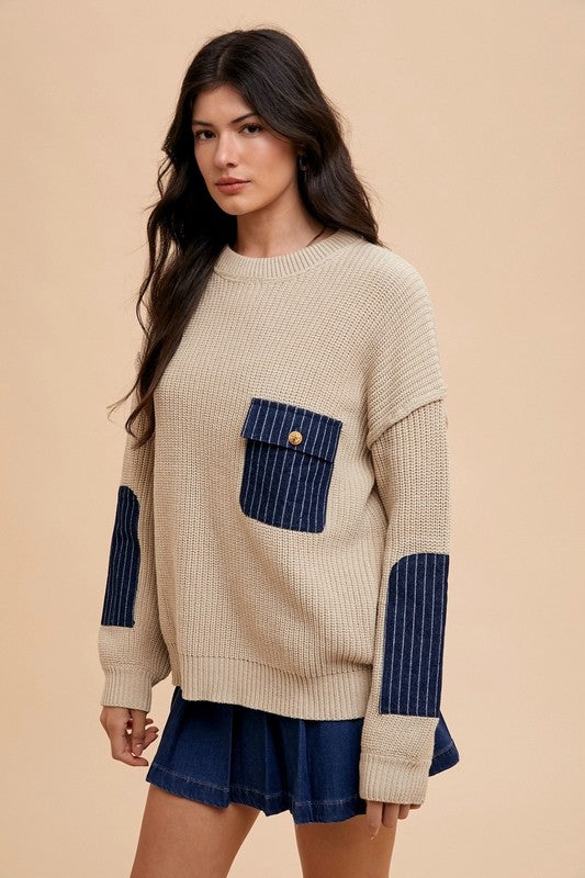 Annie Wear cozy beige sweater with patch pocket and blue contrast detailing, styled with a denim skirt.