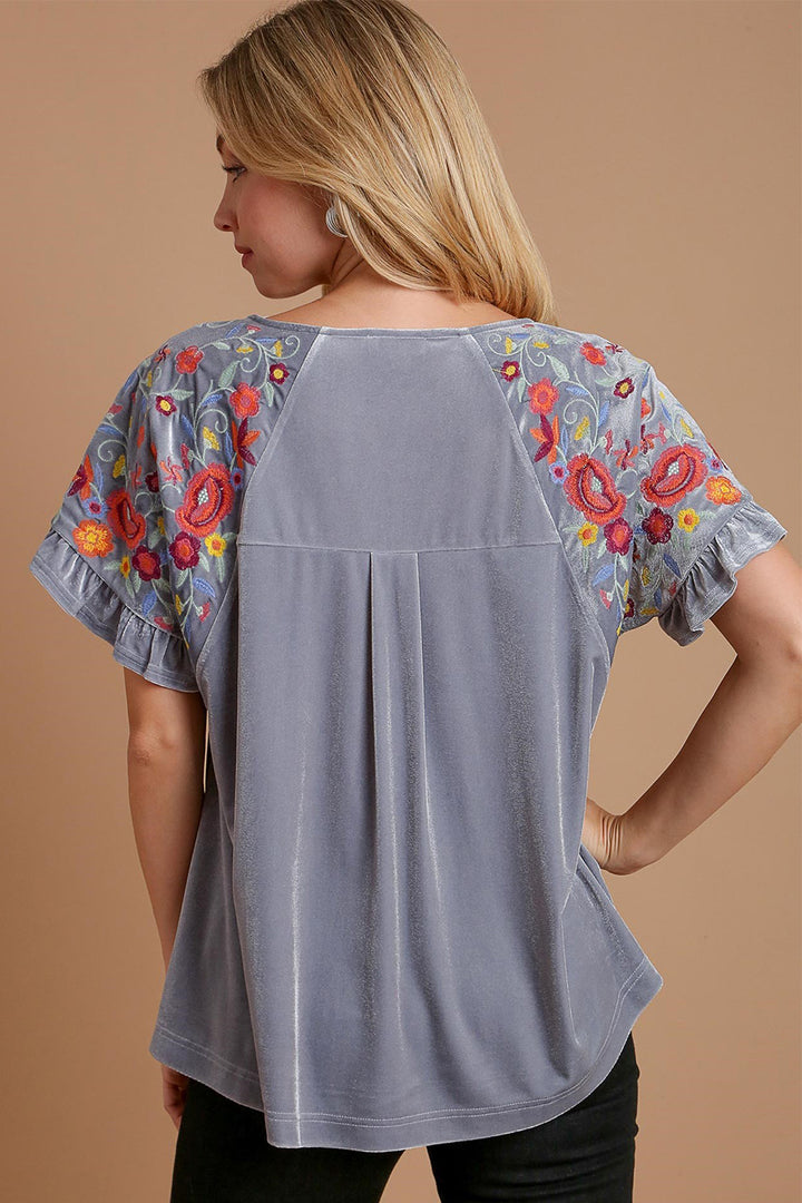 Woman modeling Umgee Velvet Embroidery Short Sleeve Blouse with colorful floral embroidery on sleeves.