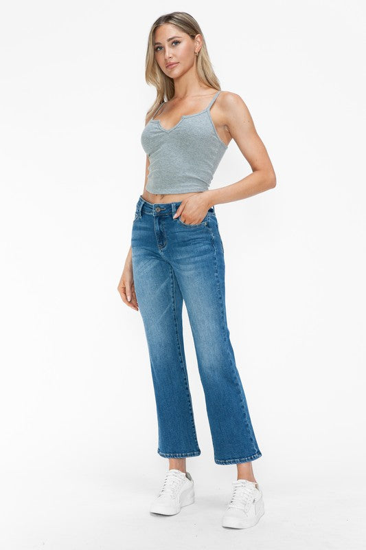 Model wearing bytos Cat's Whiskers mid rise ankle jeans with grey crop top and white sneakers in a stylish pose.