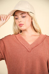 Model wearing a two-tone ribbed V-neck top and a beige cap, showcasing a cozy autumn style.