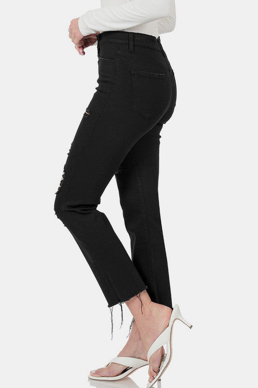 Distressed raw hem cropped jeans in black, styled with a fitted top and heels, showcasing a contemporary casual look.