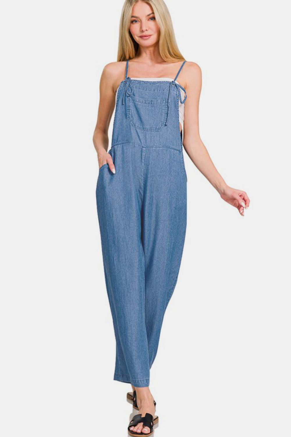 Woman wearing washed adjustable strap wide leg denim overalls, showcasing a trendy and casual style.