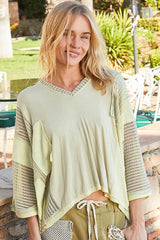 Woman wearing a stylish POL high-low contrast V-neck top in light green with oversized fit and drop shoulder design.