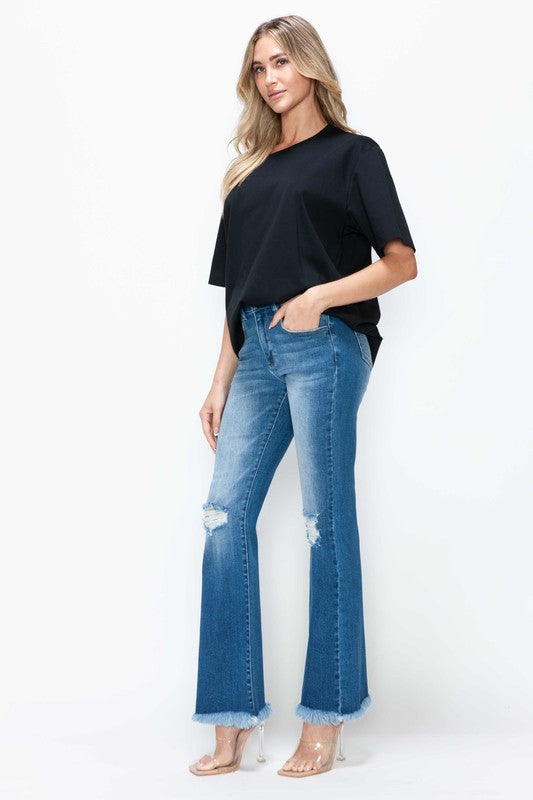 Woman wearing bytos full size raw hem distressed high rise bootcut jeans and a black top, showcasing trendy casual style.