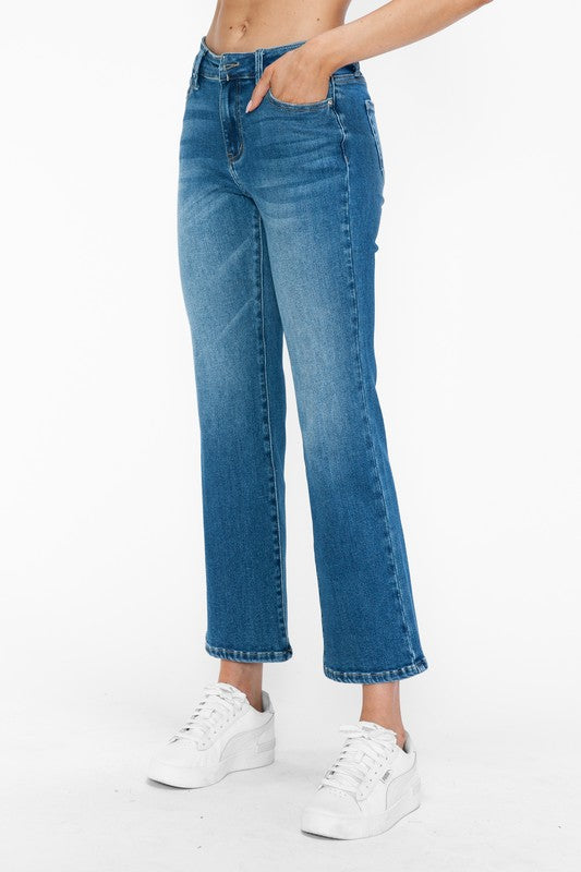 Model showcasing bytos Cat's Whiskers Mid Rise Ankle Jeans in a chic blue denim style, paired with white sneakers.